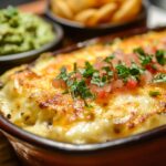 A beautifully plated enchilada dish with golden, bubbly cheese and a side of creamy guacamole and zesty salsa.